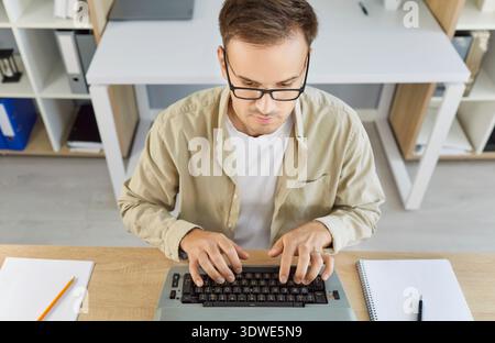 Focused writer editing page on vintage typewriter at modern home office workspace Stock Photo