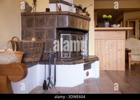 A charming rustic fireplace featuring a classic design with wicker baskets filled with firewood. The cozy ambiance is enhanced by warm wooden accents Stock Photo