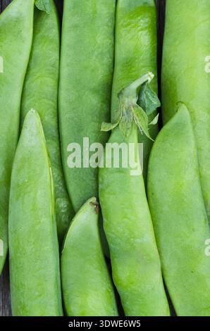 Macro image showcasing the vibrant green texture of fresh pea pods. The surface details are highlighted against a rustic wooden background, capturing Stock Photo