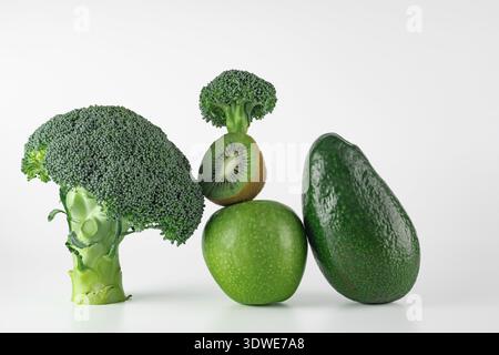 A selection of organic green produce including broccoli, avocado, kiwi, and apple arranged on a plain white background, showcasing their freshness and Stock Photo