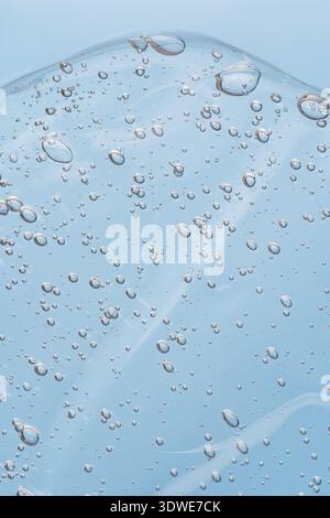 A close-up of a clear gel surface captures tiny air bubbles suspended within, creating an intriguing texture and abstract pattern against a light blue Stock Photo