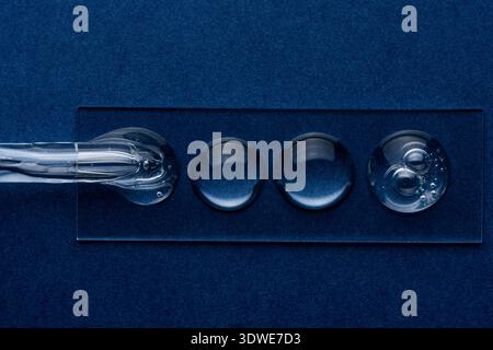 Close-up of clear gel droplets on a reflective surface, highlighting smooth texture and scientific feel. Perfect for cosmetics or science-focused cont Stock Photo