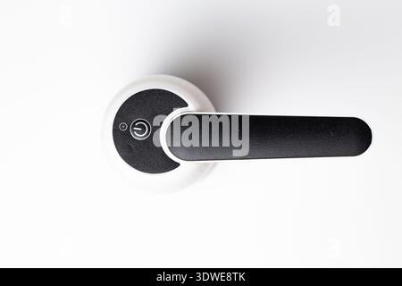 White automatic soap dispenser with black lever close-up on white background. Stock Photo