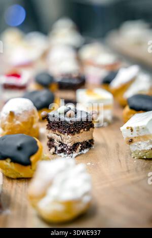 A delectable array of assorted cakes and sweets elegantly presented on a wooden platter, showcasing a variety of textures and flavors perfect for culi Stock Photo