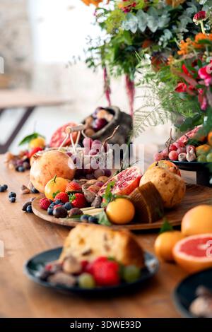 A colorful assortment of fresh fruits such as strawberries, blueberries, and grapes, alongside cheese and panettone, arranged appealingly on a wooden Stock Photo