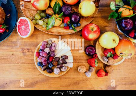 A colorful assortment of fresh fruits and nuts displayed on a wooden table, featuring strawberries, blueberries, grapes, and more, creating a delightf Stock Photo