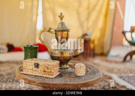 A collection of vintage objects on a round wooden table, showcasing historical craftsmanship. Includes an ornate brass teapot, a textured box, and a s Stock Photo