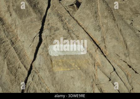 Close-up of a trail marker painted on a rock in Collado Jermoso, Picos de Europa, guiding hikers through rugged mountain terrain amid natural beauty. Stock Photo