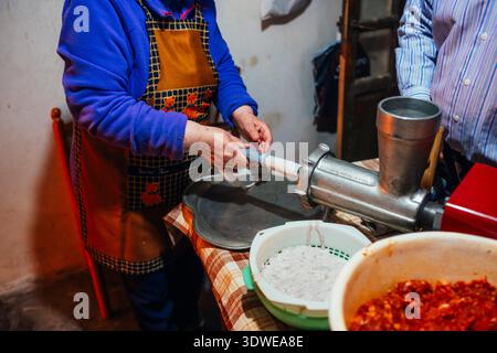 An individual in a rustic kitchen crafts chorizo sausage using minced pork. The scene highlights the traditional methods and cultural significance of Stock Photo