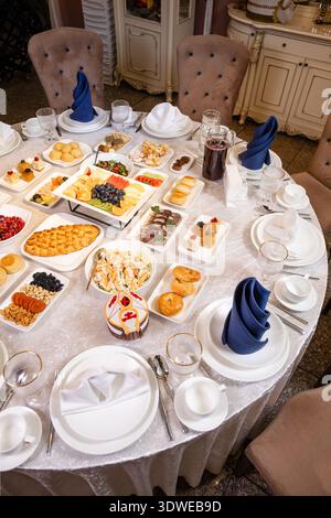 Round banquet table with appetizers, fruits, and desserts setup Stock Photo