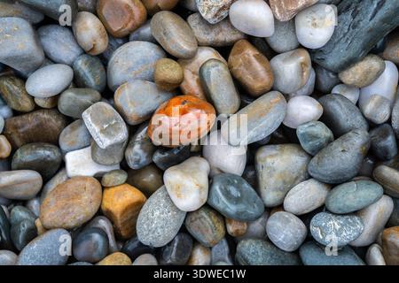 A collection of smooth stones in various earthy colors, forming a natural pattern. Captures the geological texture commonly found in cliff and rock fo Stock Photo