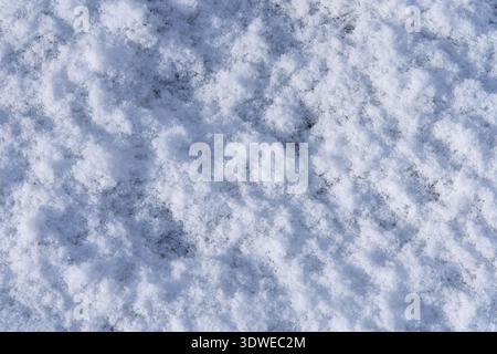 A detailed close-up of fresh snow, capturing the soft texture and subtle shadows. The snow creates a serene and calming atmosphere, highlighting its p Stock Photo