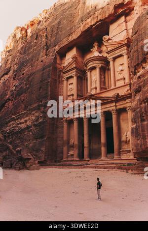 A traveler stands before the magnificent stone-carved architecture of the ancient city of Petra in Jordan, surrounded by the beautiful and timeless de Stock Photo