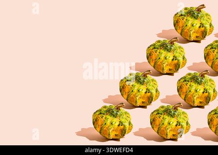 A vibrant pattern of green and orange pumpkins on a neutral backdrop perfect for festive Halloween decoration. The playful arrangement brings a season Stock Photo