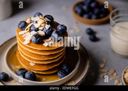 A mouthwatering breakfast scene featuring a stack of pancakes topped with fresh blueberries and almond slices. A perfect start to the day with a touch Stock Photo