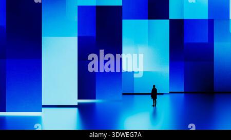 A man stands still in front of a large digital screen displaying blue geometric shapes. Stock Photo