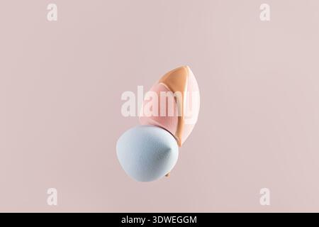 Close-up of beige liquid foundation swatches on soft pink and blue makeup sponges over a pastel background. Ideal for beauty, cosmetics, and makeup co Stock Photo