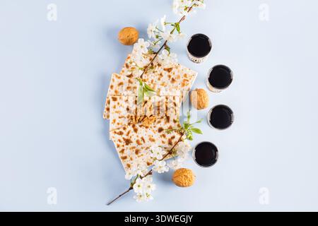 A traditional Passover table setting featuring matzah, symbolic red wine, and walnuts, beautifully arranged with flowering branches on a soft blue bac Stock Photo