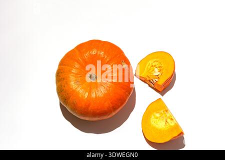 A vibrant whole pumpkin accompanied by two sliced sections against a clear white background. Highlighting its fresh, nutritious qualities, ideal for d Stock Photo