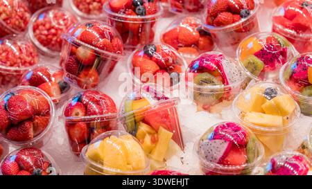 A vivid display of fresh fruit cups filled with strawberries, kiwi, pineapple, and other fruits. The arrangement offers a colorful, textured pattern a Stock Photo