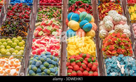 An array of colorful candies in transparent bins at a market, showcasing various shapes and textures. A vibrant display of sweet treats in a candy sho Stock Photo