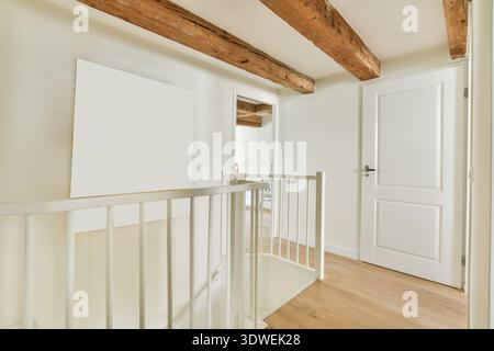 A stylish hallway featuring wooden beams and a vibrant piece of abstract art. Light colors enhance the spacious atmosphere. Stock Photo