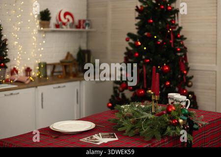 Cozy dining room adorned for Christmas with a beautifully decorated tree and festive table setting. Red accents and warm lights create a charming holi Stock Photo