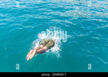A person dives into the clear, refreshing waters of the Mediterranean Sea, creating a splash amidst the vibrant blue waves, capturing the excitement o Stock Photo