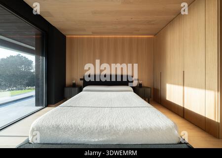 The serene elegance of a minimal luxury bedroom in Cantabria, Spain, showcasing modern architecture with a sleek design and warm wood finishes, creati Stock Photo
