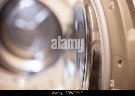 Dryer interior showing clean perforated stainless steel drum ready for clothes. Clean metallic drum inside washing machine for laundry tasks. Stock Photo
