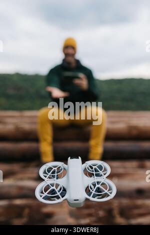 A man operates a drone in a scenic outdoor setting, emphasizing technology and exploration. The landscape serves as a serene backdrop, combining natur Stock Photo