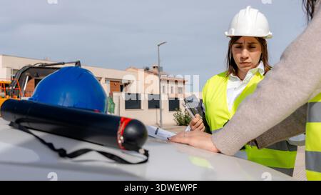 A female architect and technical engineer collaborate on a construction site, discussing plans and reviewing project details while surrounded by build Stock Photo