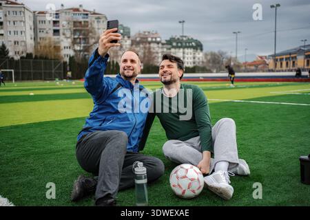 Friends taking selfie on soccer field after training Stock Photo