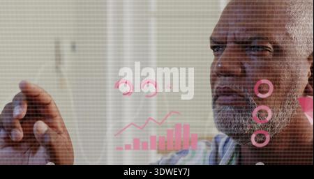 Extending senior man in striped shirt manipulating hologram at home office, pink charts, copy space Stock Photo
