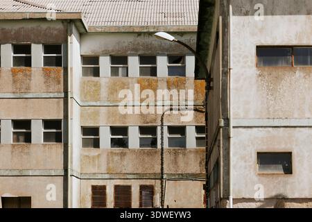 A weathered, industrial building facade featuring aging concrete and small windows. The structure showcases years of wear, adding character with its r Stock Photo