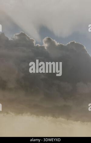 Captivating image of dark storm clouds with sun rays piercing through, creating a dramatic contrast between light and shadow in the sky. The scene evo Stock Photo