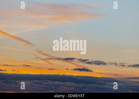 A stunning sunset sky features a mix of vibrant orange, pink, and blue hues with scattered clouds, capturing the serene beauty of dusk as day transiti Stock Photo