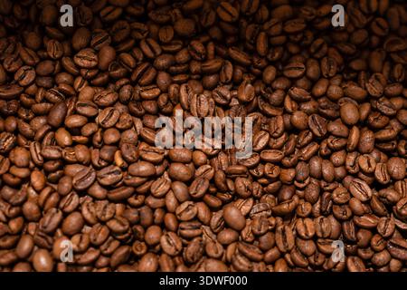 A detailed close-up of freshly roasted coffee beans showcasing their rich texture and brown hues, ideal for illustrating the aromatic essence of coffe Stock Photo