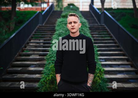 Urban portrait of a young man in a black sweater, set against the modern backdrop of Kyiv's architecture. The scene captures the essence of contempora Stock Photo