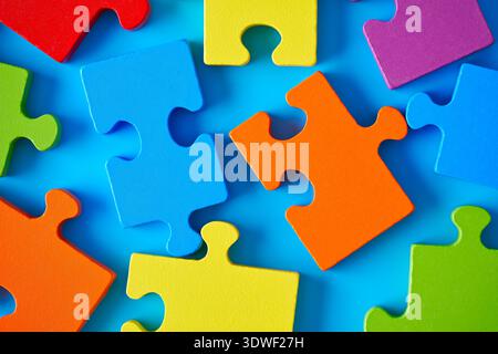 Vibrant jigsaw puzzle pieces scattered on a blue surface symbolizing autism and mental development. The pieces represent complexity, strategy, and bra Stock Photo
