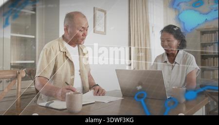 Writing pair reading papers and using laptop at home table, wearing short sleeves, blue overlay Stock Photo