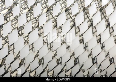 A close up shot of a contemporary architectural roof structure featuring white diamond shaped panels on a complex metal frame. Stock Photo