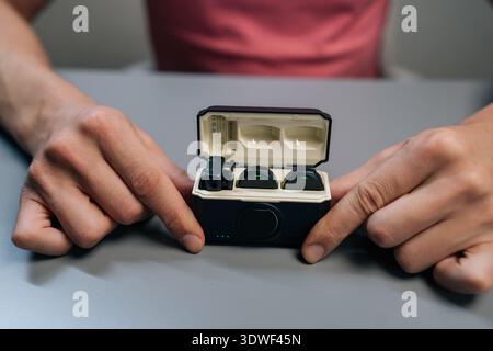 Content creator examining modern wireless microphone system, opening charging case, checking transmitter and accessories before connecting to Stock Photo
