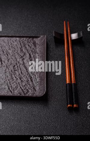 An empty ceramic square black plate with chopsticks for Asian food. An empty square plate as a food background for your design Stock Photo