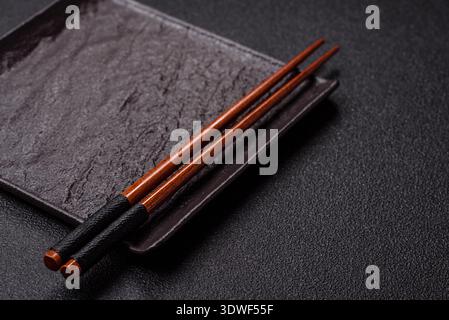 An empty ceramic square black plate with chopsticks for Asian food. An empty square plate as a food background for your design Stock Photo
