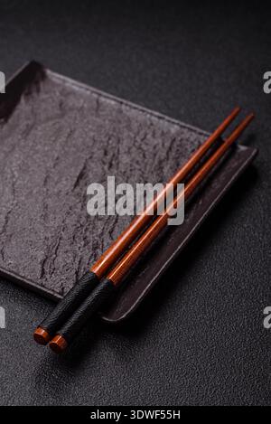An empty ceramic square black plate with chopsticks for Asian food. An empty square plate as a food background for your design Stock Photo