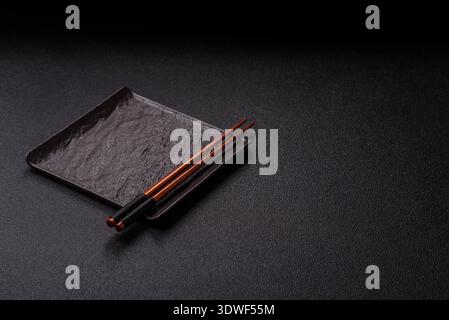 An empty ceramic square black plate with chopsticks for Asian food. An empty square plate as a food background for your design Stock Photo