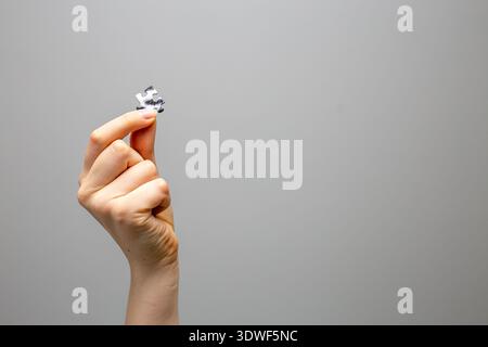 Hand holding a single jigsaw puzzle piece against a plain background. Concept image symbolizing problem solving, final solution, completing a project Stock Photo