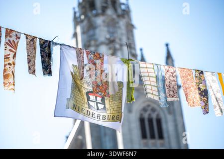 Description: Fabric garlands hang in an alleyway in Niederburg, with the cathedral visible in the background. Konstanz, Baden-Württemberg, Germany. Stock Photo