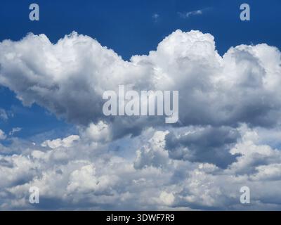 Massive white cumulus clouds form a dramatic textured sky against a deep-blue backdrop, suggesting summer weather, openness and atmosphere, suitable f Stock Photo
